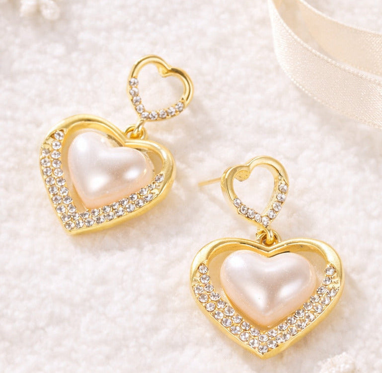 Gold heart-shaped earrings with pearls on a white background