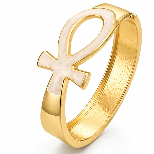 A gold bracelet featuring an openwork Ankh symbol with a pearlescent white inlay, set against a clean white background.
