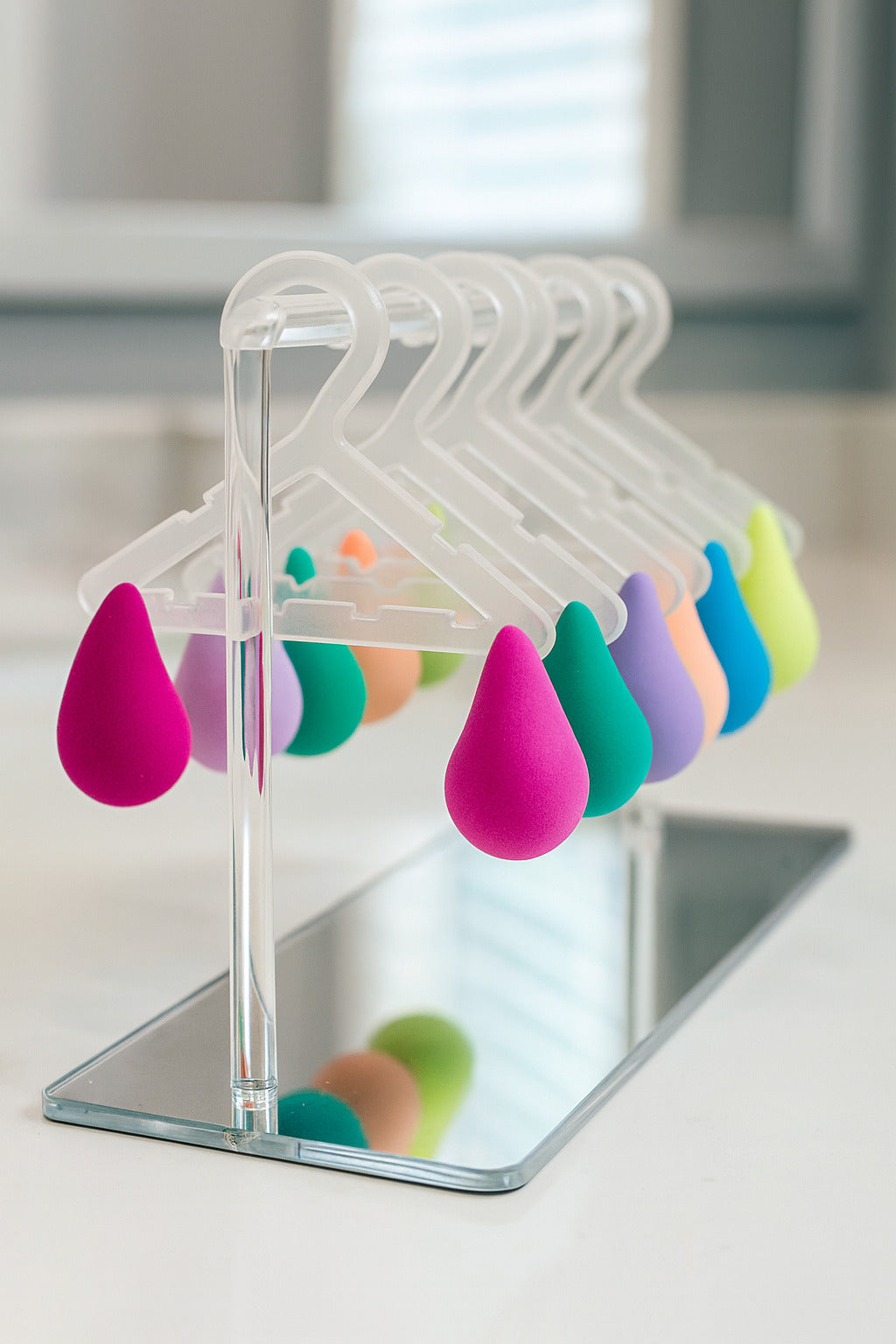 Colorful teardrop-shaped objects on clear hangers with a mirror background