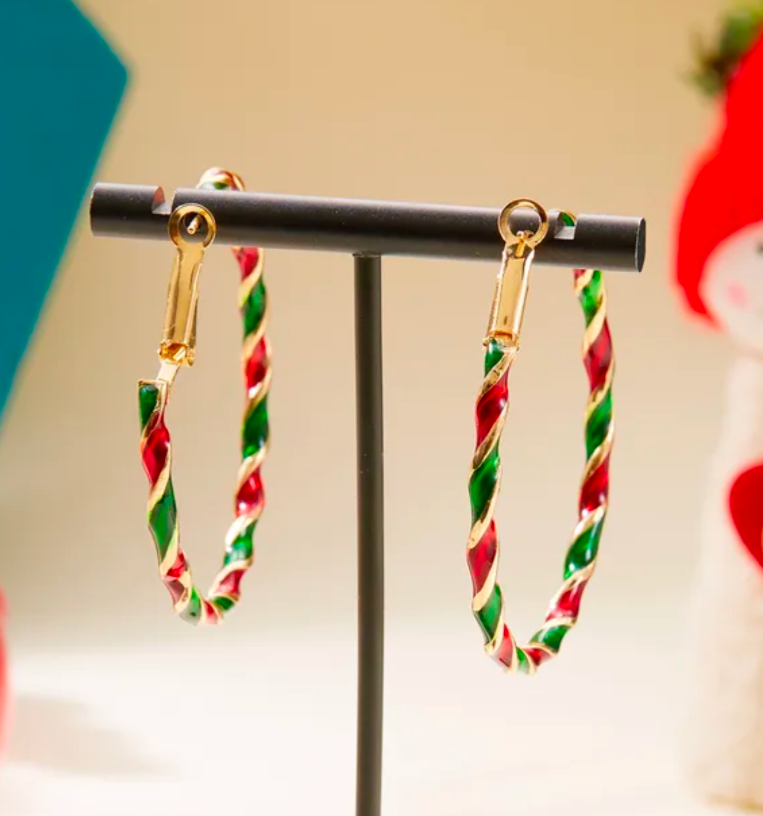 Candy cane hoop earrings on a black stand with a blurred background