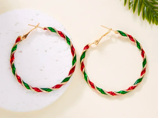 Pair of hoop earrings with red and green braided design on a white surface.