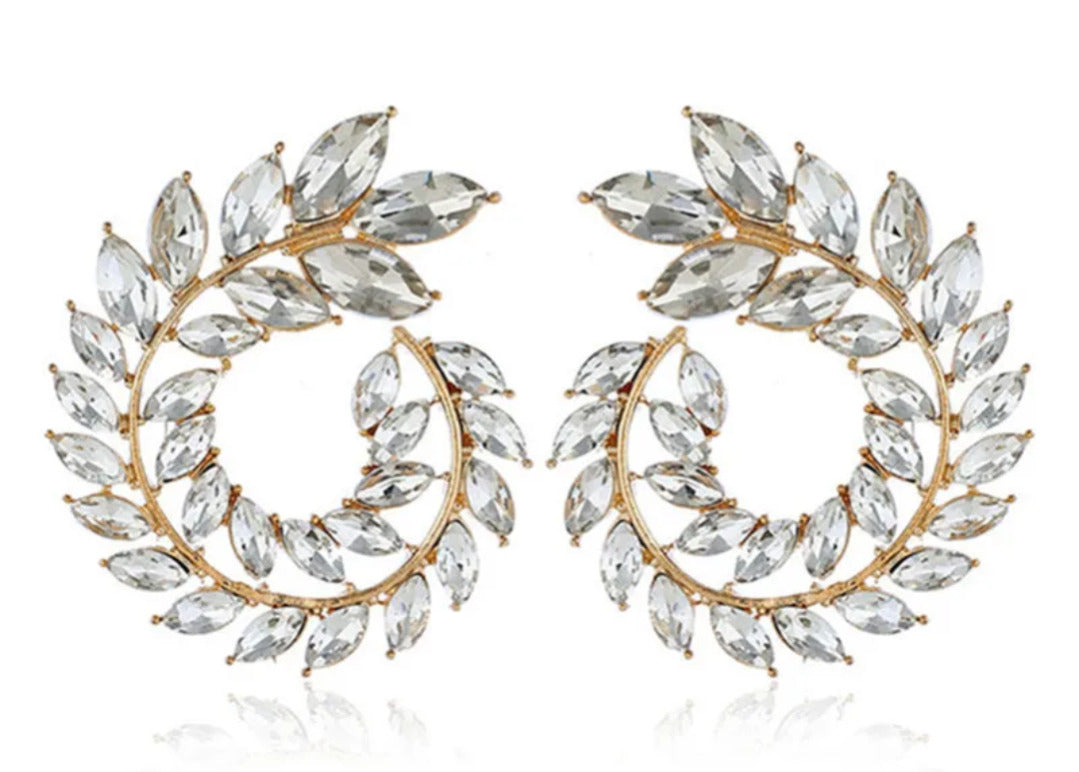 Pair of gold and crystal leaf-shaped earrings on a white background