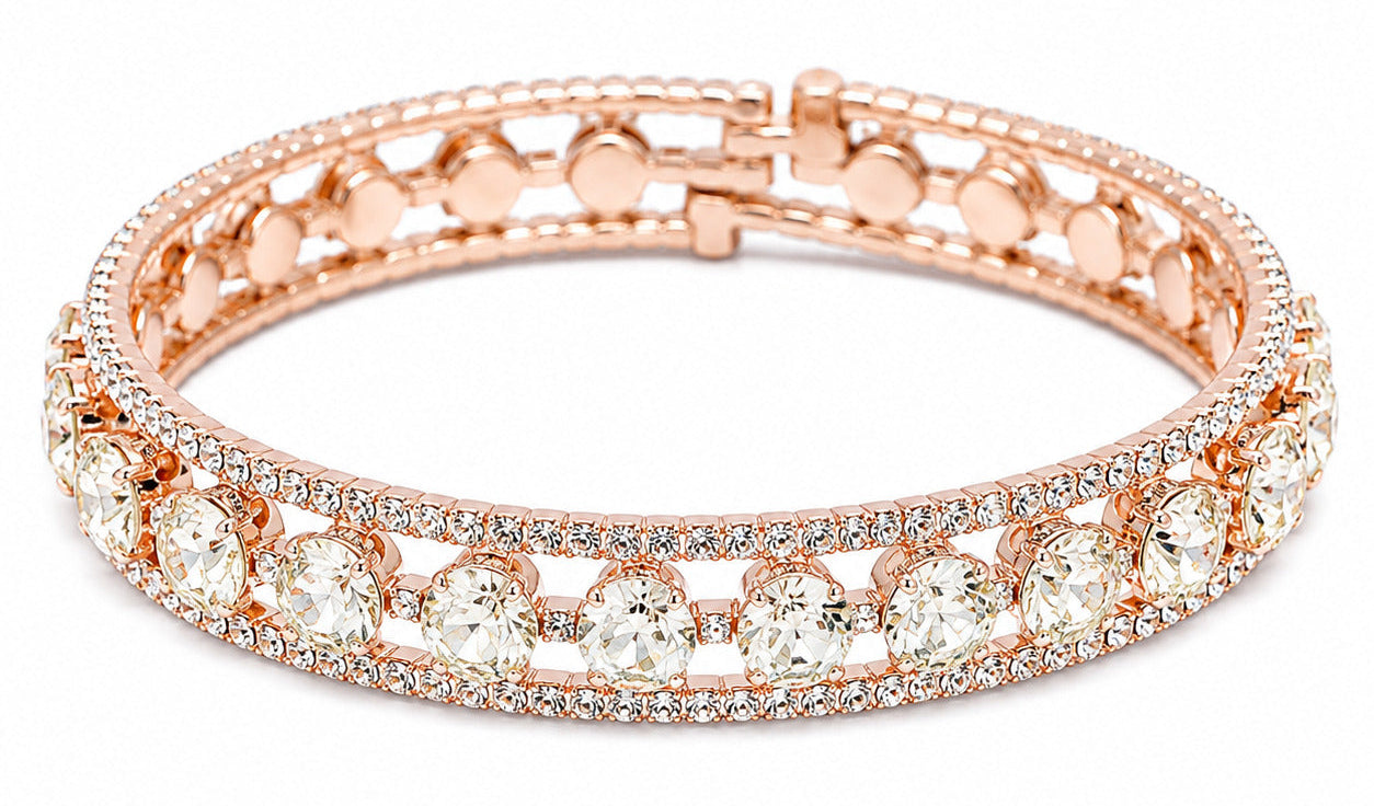 A rose gold bangle bracelet featuring rows of clear round-cut stones and pavé-set small stones, shown on a plain white background.
