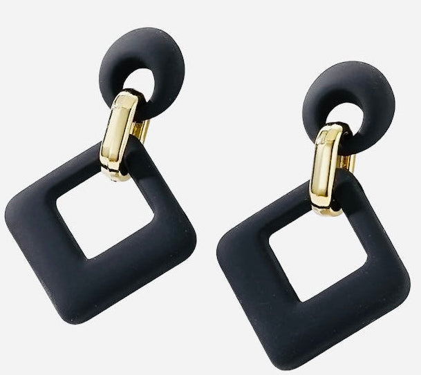 A person wearing the velvet rhombus drop earrings with a gold clip attachment, showcasing the earrings in an orange and black color.