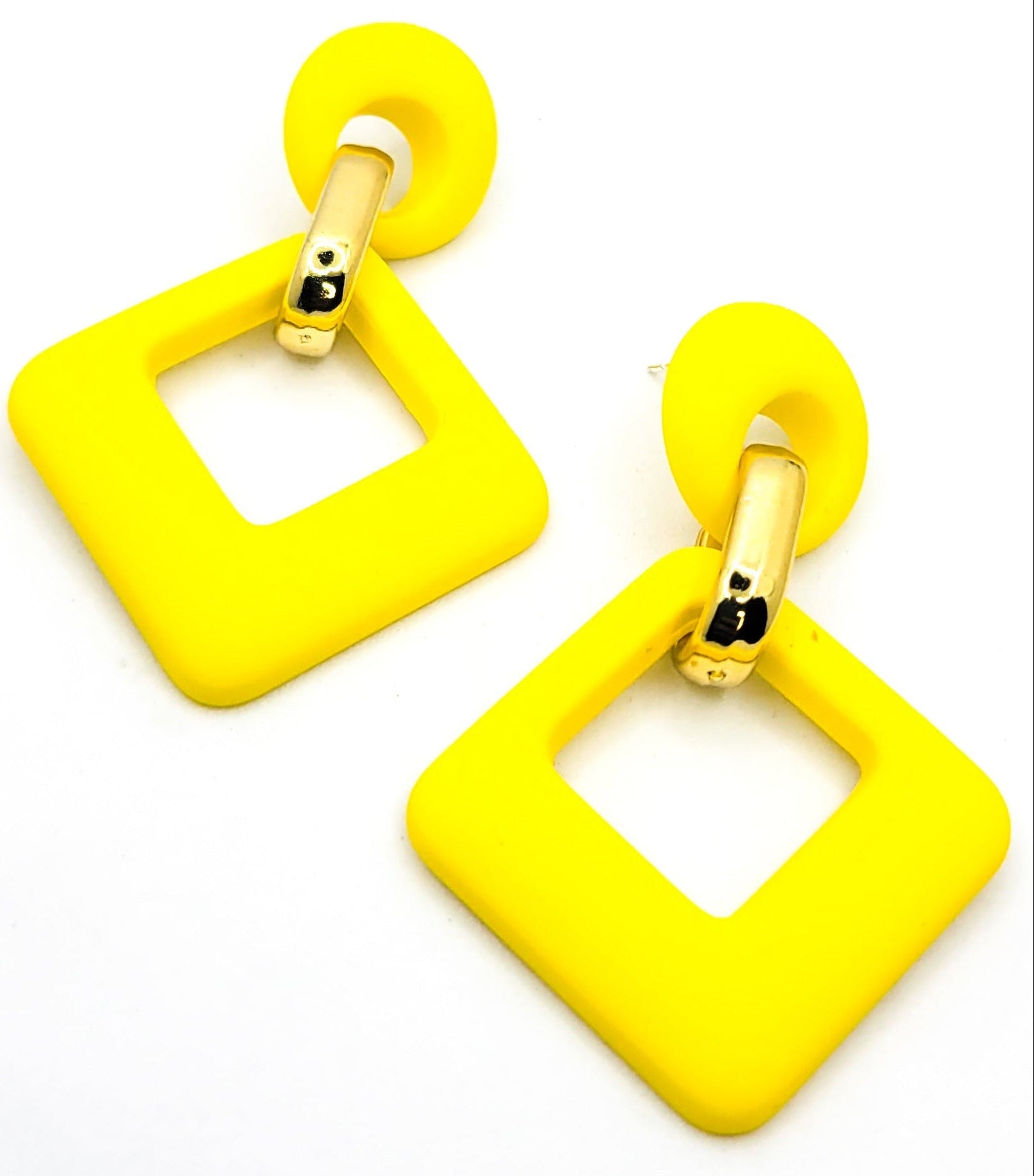A person wearing the velvet rhombus drop earrings with a gold clip attachment, showcasing the earrings in an orange and black color.