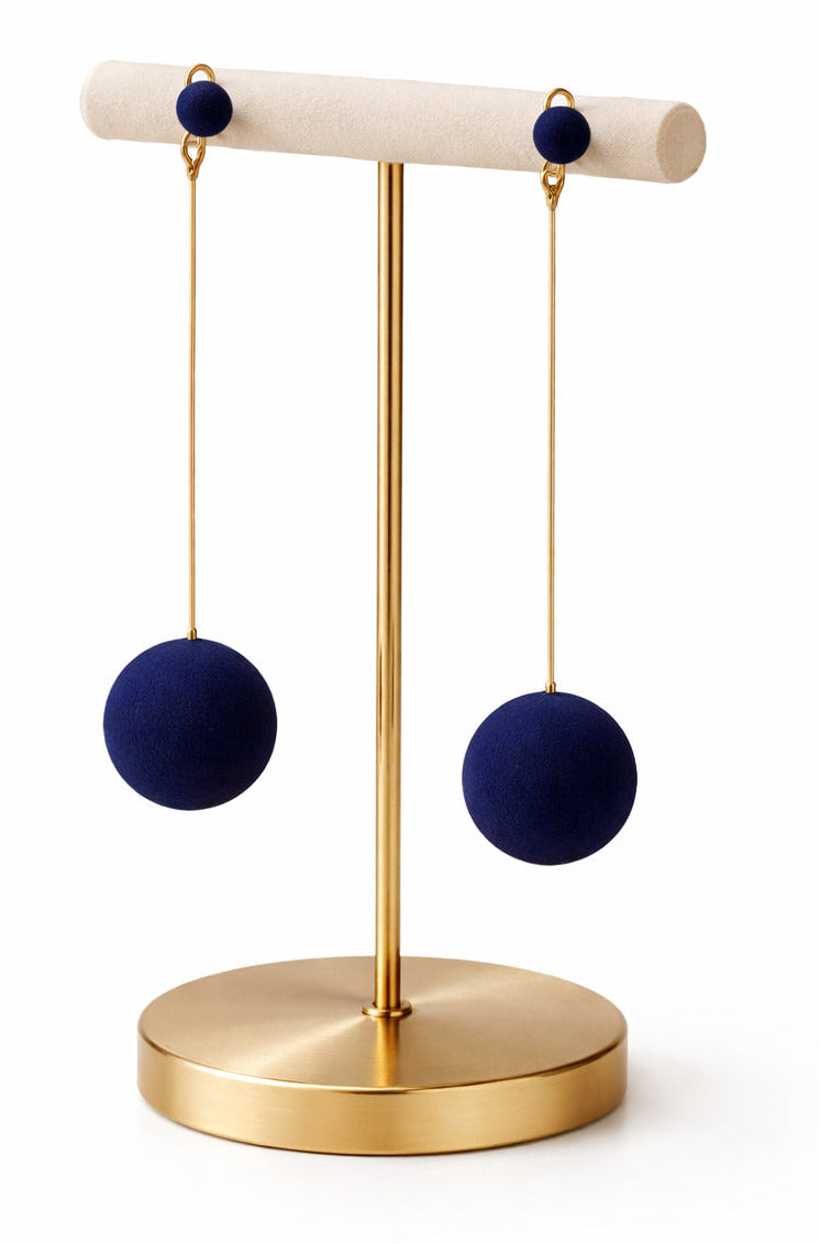 Pair of navy blue earrings on a gold stand against a white background